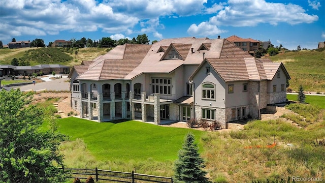 back of property featuring a balcony and a lawn