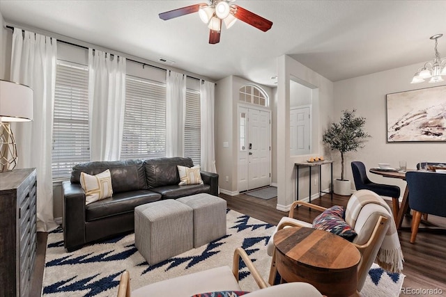 living room featuring baseboards, ceiling fan with notable chandelier, light wood-type flooring, and visible vents