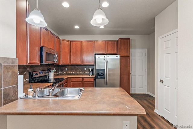 kitchen featuring decorative light fixtures, a sink, a peninsula, dark wood-style floors, and stainless steel appliances