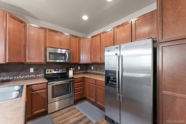 kitchen featuring light wood-style floors, light countertops, decorative backsplash, and appliances with stainless steel finishes