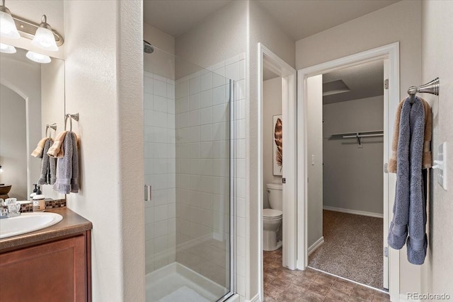 bathroom with vanity, a spacious closet, toilet, and a shower stall