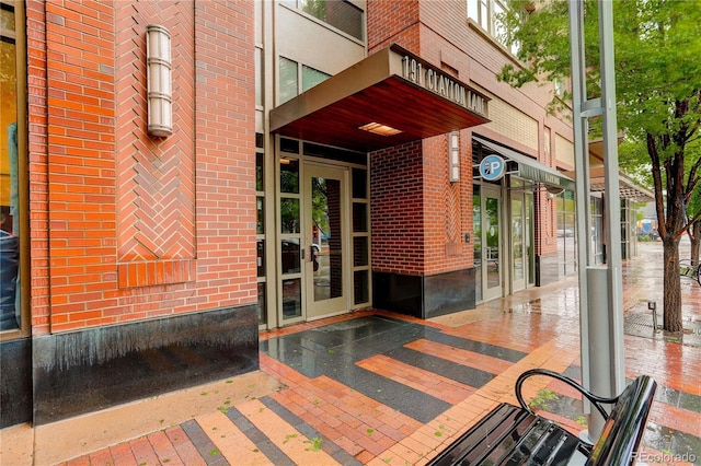 view of exterior entry featuring brick siding and french doors