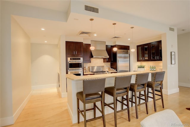 kitchen featuring wall chimney exhaust hood, built in refrigerator, backsplash, baseboards, and recessed lighting