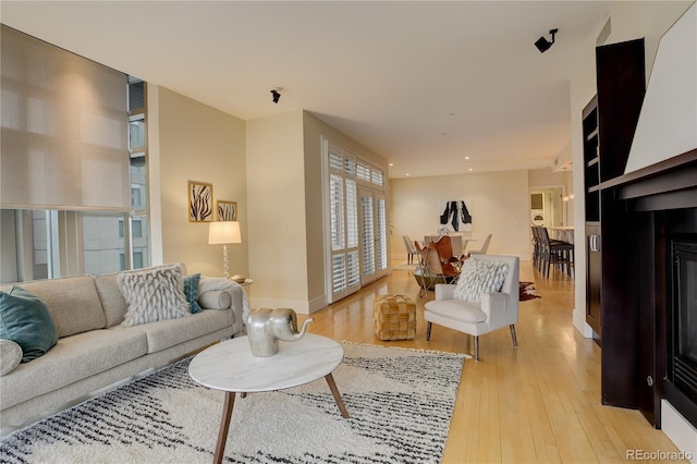 living area with light wood-type flooring, recessed lighting, and a glass covered fireplace