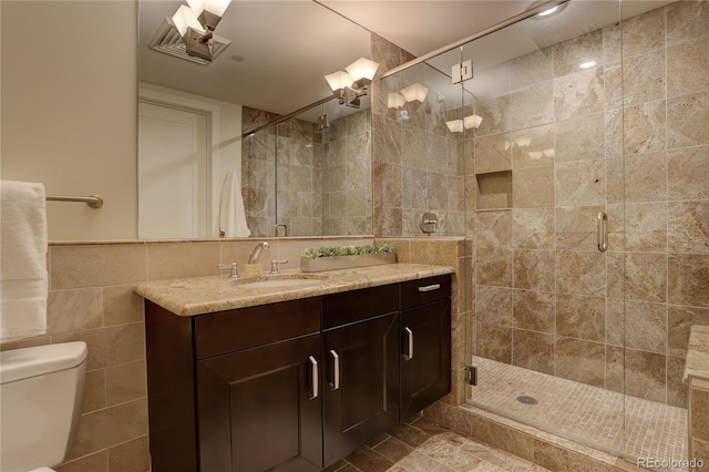 bathroom featuring tile walls, a stall shower, vanity, and toilet