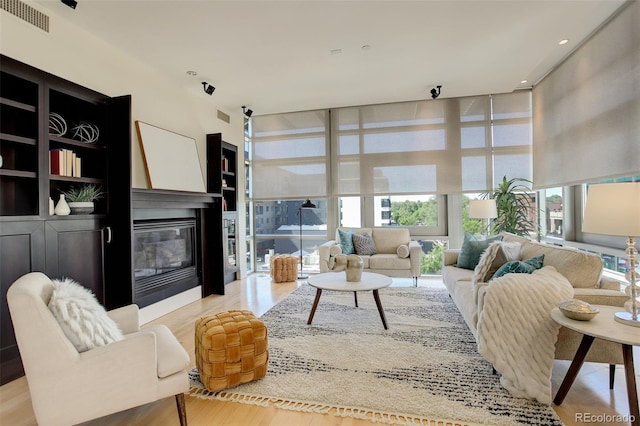 191 Clayton Ln Unit 402, Denver, CO 80206 - living room featuring wood finished floors, a glass covered fireplace, and a wall of windows