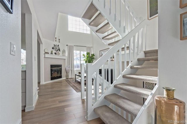 stairway with hardwood / wood-style floors and a towering ceiling