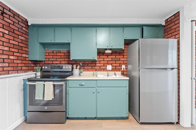 1413 S Bryan Ave, Fort Collins, CO 80521 - kitchen featuring freestanding refrigerator, stainless steel electric range, brick wall, light countertops, and light wood-style flooring