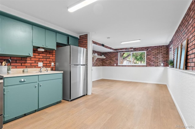1413 S Bryan Ave, Fort Collins, CO 80521 - kitchen with freestanding refrigerator, brick wall, light wood-style flooring, and light countertops