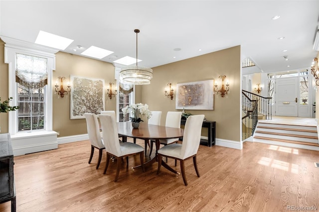 465 Monroe St, Denver, CO 80206 - dining room featuring a chandelier, light wood-type flooring, stairway, a skylight, and baseboards