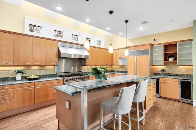 465 Monroe St, Denver, CO 80206 - kitchen with under cabinet range hood, stainless steel gas stove, beverage cooler, light wood-style flooring, and a kitchen island
