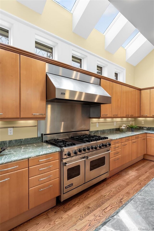 465 Monroe St, Denver, CO 80206 - kitchen with range with two ovens, ventilation hood, a skylight, light wood-type flooring, and dark countertops
