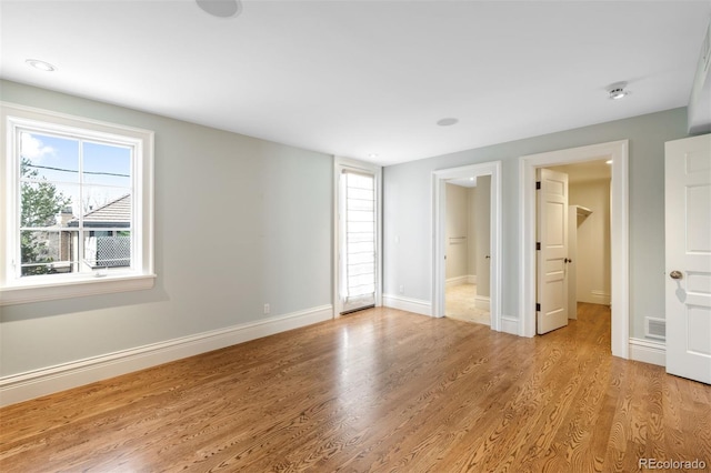 465 Monroe St, Denver, CO 80206 - unfurnished bedroom with multiple windows, light wood-style flooring, baseboards, and ensuite bathroom