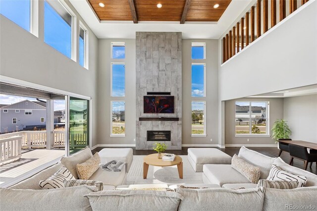 living room featuring wood ceiling, a high ceiling, a fireplace, and beamed ceiling