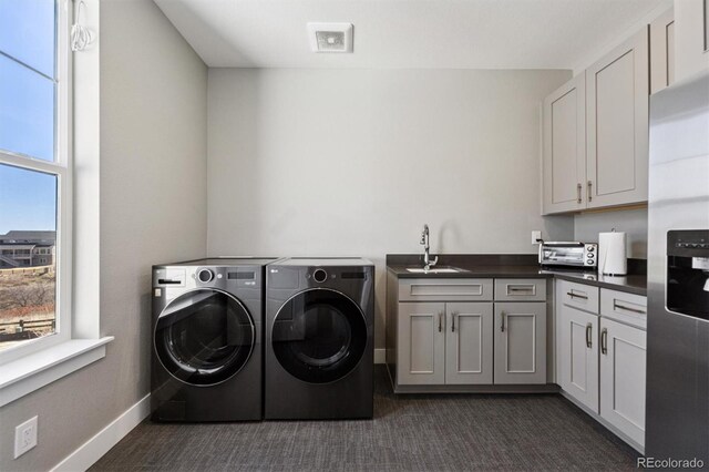 clothes washing area with a sink, separate washer and dryer, dark colored carpet, and cabinet space