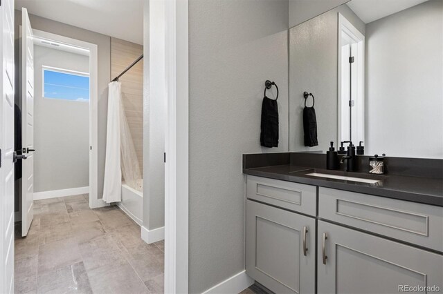 bathroom with baseboards, shower / bath combo, and vanity