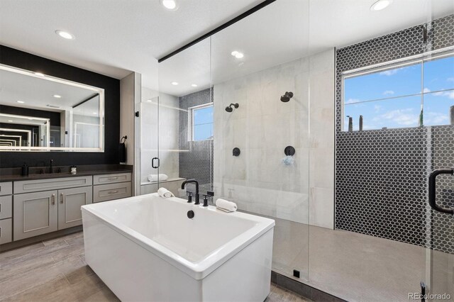 full bath featuring vanity, recessed lighting, a freestanding tub, and a stall shower