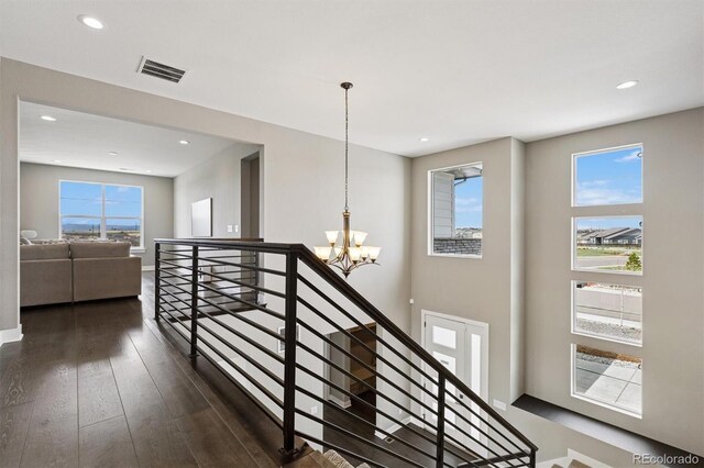 stairs featuring an inviting chandelier, visible vents, wood finished floors, baseboards, and recessed lighting