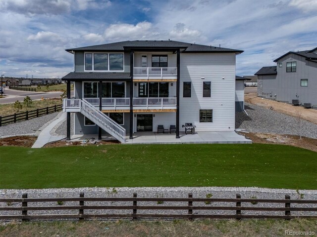 rear view of house featuring a lawn, a patio, fence, and a balcony