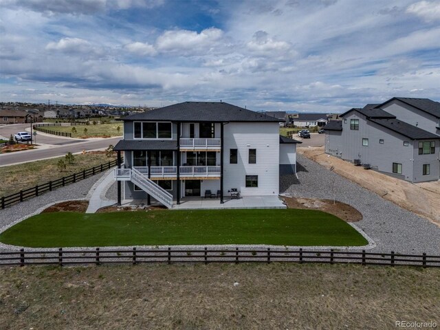 rear view of property with a balcony, a fenced backyard, a patio area, a yard, and stairway
