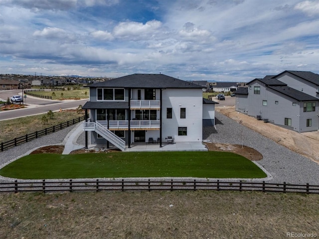 rear view of property with a fenced backyard, a yard, a patio area, and a balcony