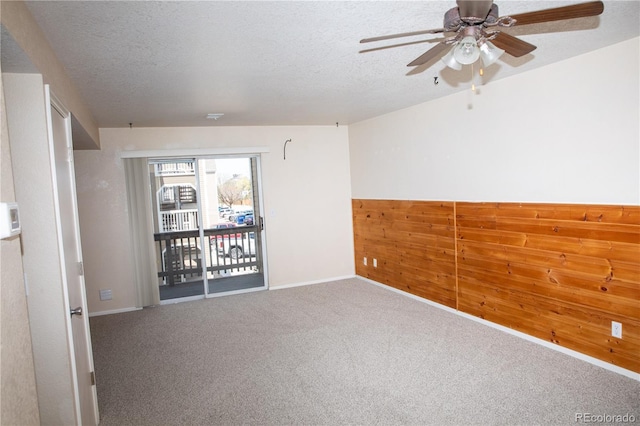carpeted spare room featuring a ceiling fan, a textured ceiling, and baseboards