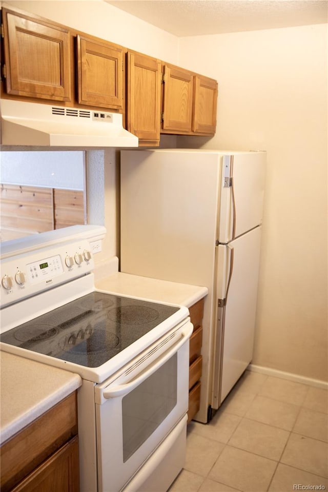 kitchen featuring white electric range oven, under cabinet range hood, light tile patterned floors, light countertops, and brown cabinets