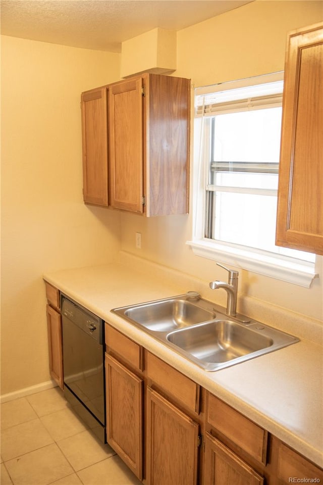 kitchen with black dishwasher, a sink, light countertops, light tile patterned flooring, and brown cabinets