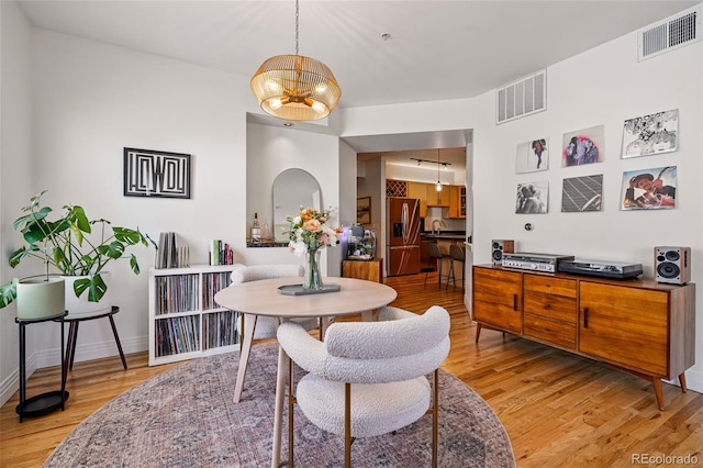 dining area with baseboards, light wood finished floors, and visible vents