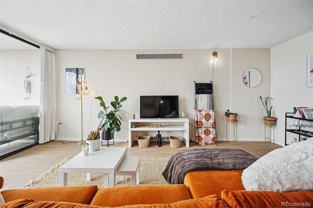 living area with light wood-style floors, baseboards, and visible vents