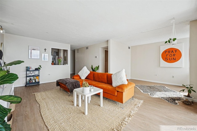 living area featuring visible vents, baseboards, and wood finished floors