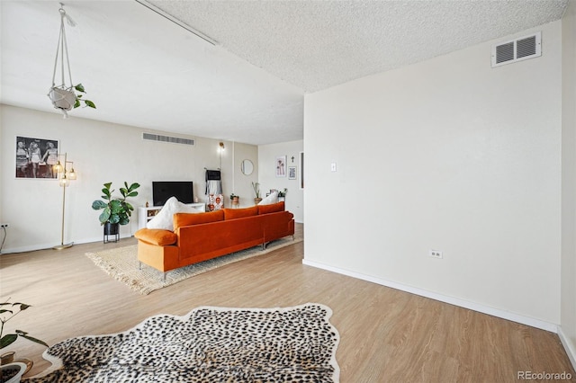 living room featuring a textured ceiling, wood finished floors, and visible vents