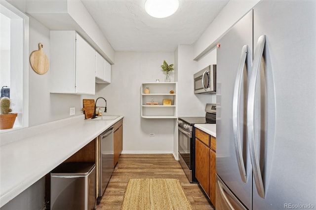 kitchen featuring stainless steel appliances, a sink, white cabinetry, light countertops, and brown cabinetry