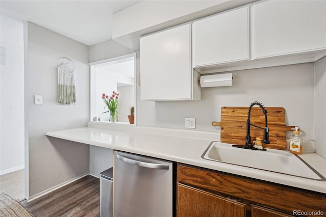 kitchen with dark wood-style flooring, a sink, white cabinets, light countertops, and dishwasher