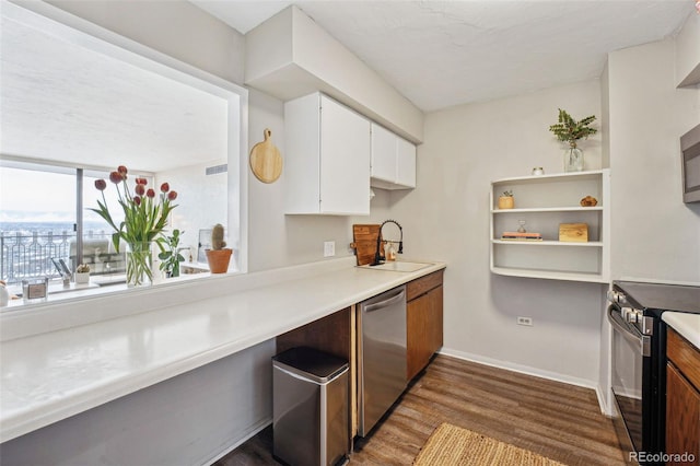 kitchen with appliances with stainless steel finishes, white cabinetry, light countertops, and a sink