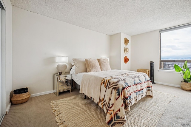 carpeted bedroom with a textured ceiling and baseboards