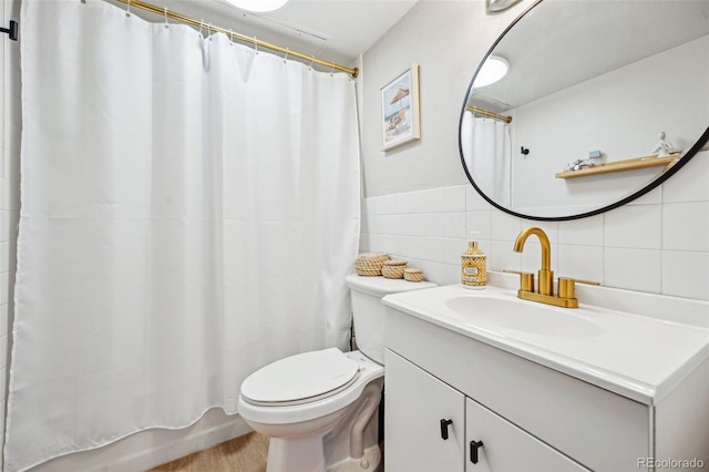 bathroom featuring tile walls, vanity, and toilet