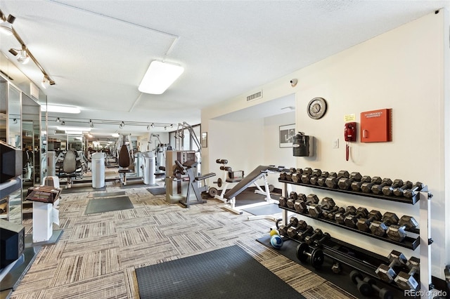 exercise room featuring carpet floors, visible vents, a textured ceiling, and track lighting