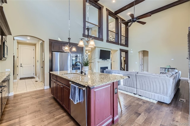 kitchen featuring sink, a center island with sink, hardwood / wood-style flooring, a breakfast bar, and a towering ceiling