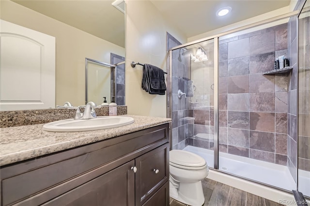 bathroom featuring an enclosed shower, hardwood / wood-style flooring, vanity, and toilet