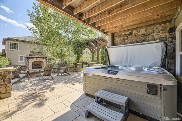 view of patio / terrace featuring a hot tub and an outdoor stone fireplace