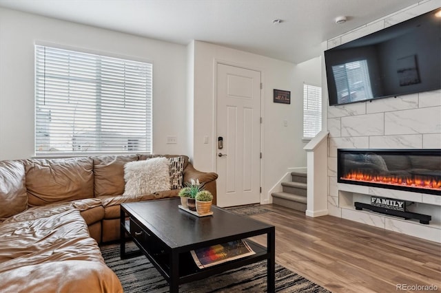 living area with stairs, a fireplace, and wood finished floors