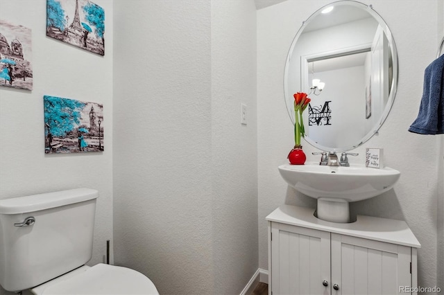 bathroom featuring toilet, baseboards, and a textured wall