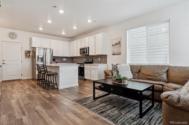 living room with light wood-style flooring and recessed lighting