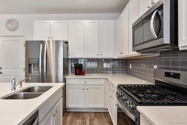 kitchen with decorative backsplash, white cabinetry, stainless steel appliances, and a sink