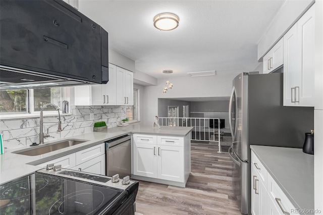 kitchen with light hardwood / wood-style flooring, stainless steel appliances, sink, kitchen peninsula, and white cabinetry