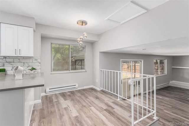 unfurnished dining area with light hardwood / wood-style flooring, a wealth of natural light, and a baseboard radiator