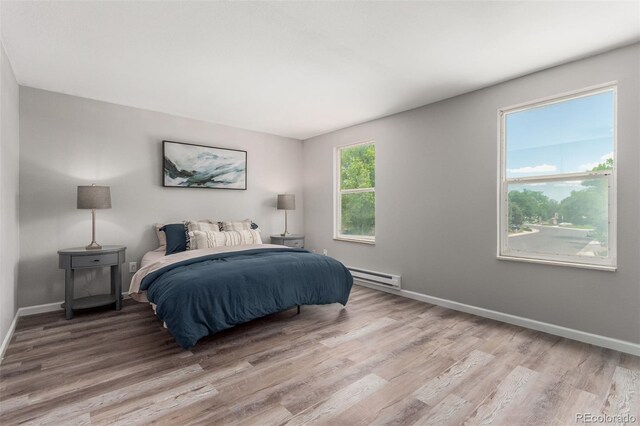 bedroom featuring a baseboard heating unit and hardwood / wood-style flooring