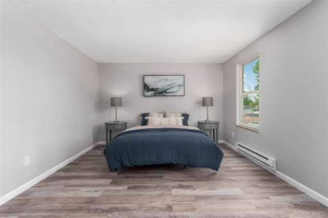 bedroom with hardwood / wood-style flooring and a baseboard heating unit