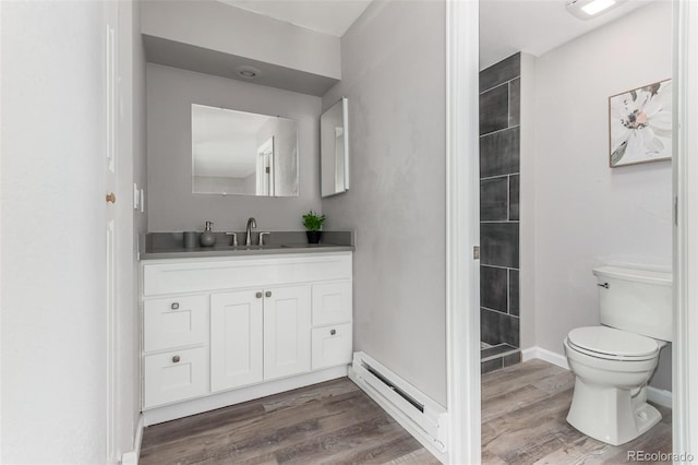 bathroom with vanity, tiled shower, toilet, and wood-type flooring